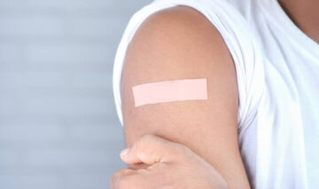 A man showing a bandage on his upper arm after getting vaccinated.